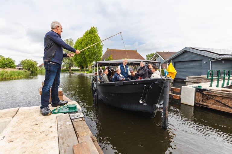 Met een klompje aan een hengel overhandigen rayonbeheerder Jeroen Hemstra en dagelijks bestuurslid Gerben de Boer van Wetterskip Fryslân het overdrachtsdocument van sluis Broek aan voorzitter Bertus Mulder van Stichting Waterschapserfgoed. Foto: Aron Weidenaar. 